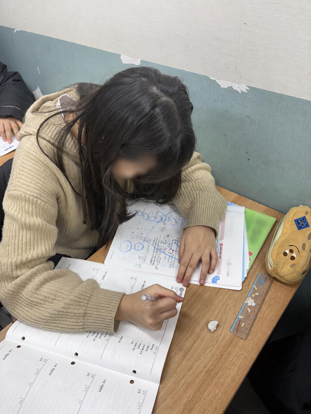 학생이 수학 문제의 풀이 과정을 집중해서 작성하는 모습
